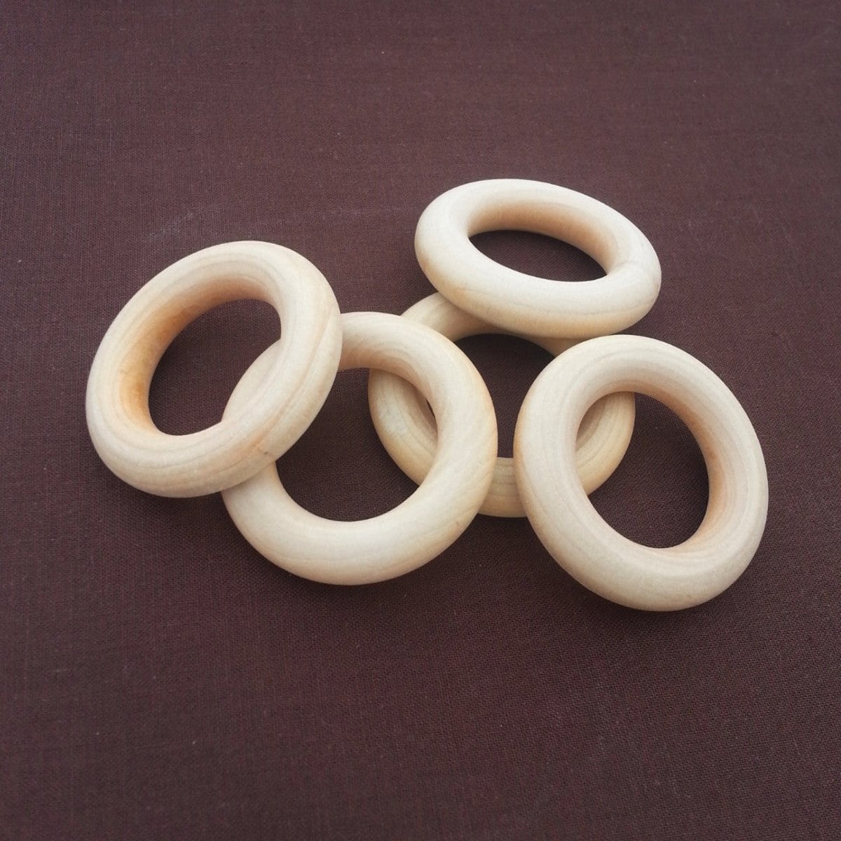 Set of untreated raw maple wooden teething rings, arranged on neutral fabric