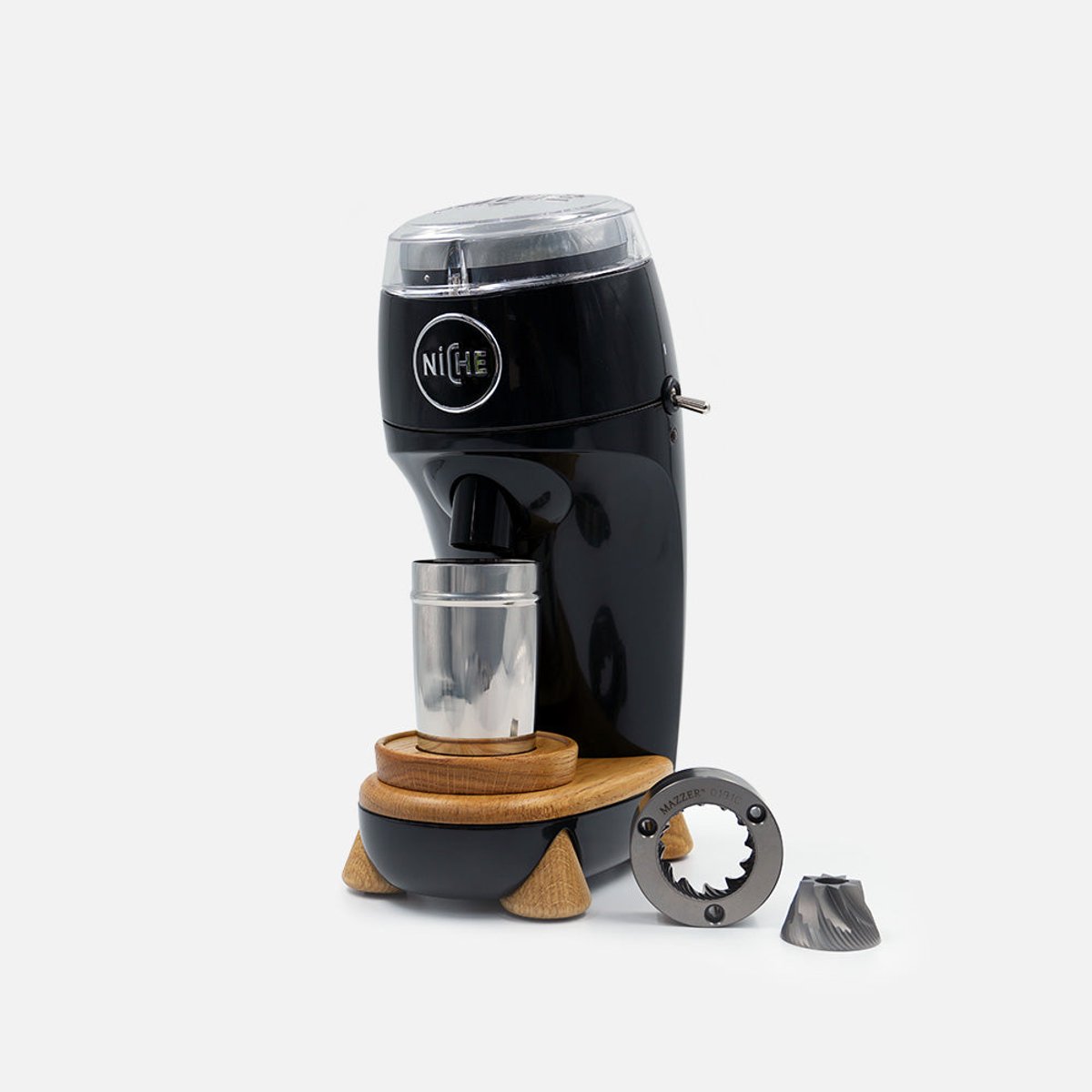Niche Zero single-dose coffee grinder in black on its oak stand, with the stainless grind cup in place and the conical burrs laid out beside it