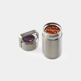 PlanetBox insulated stainless food container open, filled with alphabet soup, with its brushed steel screw lid and fold-down steel handle set beside it