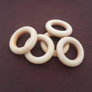 Set of untreated raw maple wooden teething rings, arranged on neutral fabric