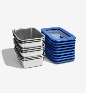 Misenware set - a stack of stainless steel food storage containers beside a stack of matching silicone-rimmed tempered glass lids